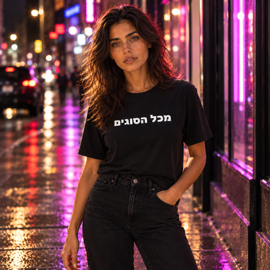 Maya wearing the black MEEHAL מכל הסוגים tee on a neon-lit street at night